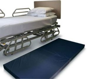 Fall mat by a nursing home bed cushions the blow from rolling out of bed